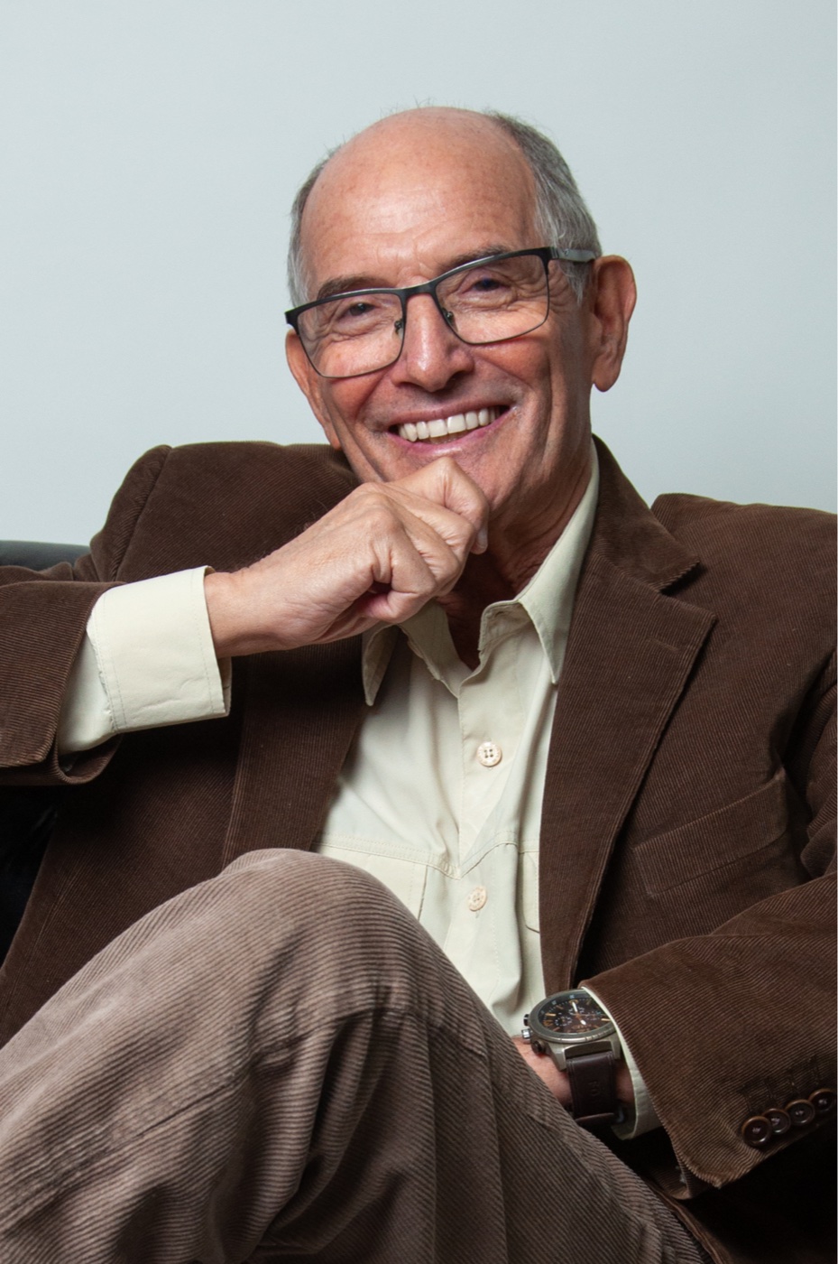 Ernesto Haberkorn sentado, sorrindo, com a mão no queixo